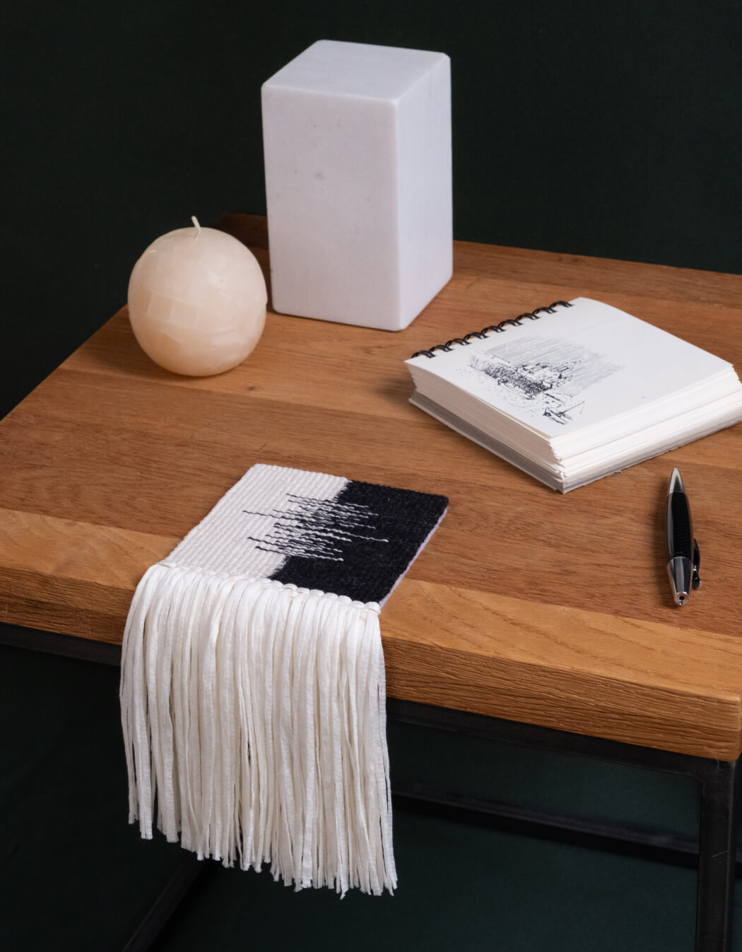 Three handwoven coasters with a mate-cup motif, on a wooden table beside a cup of tea